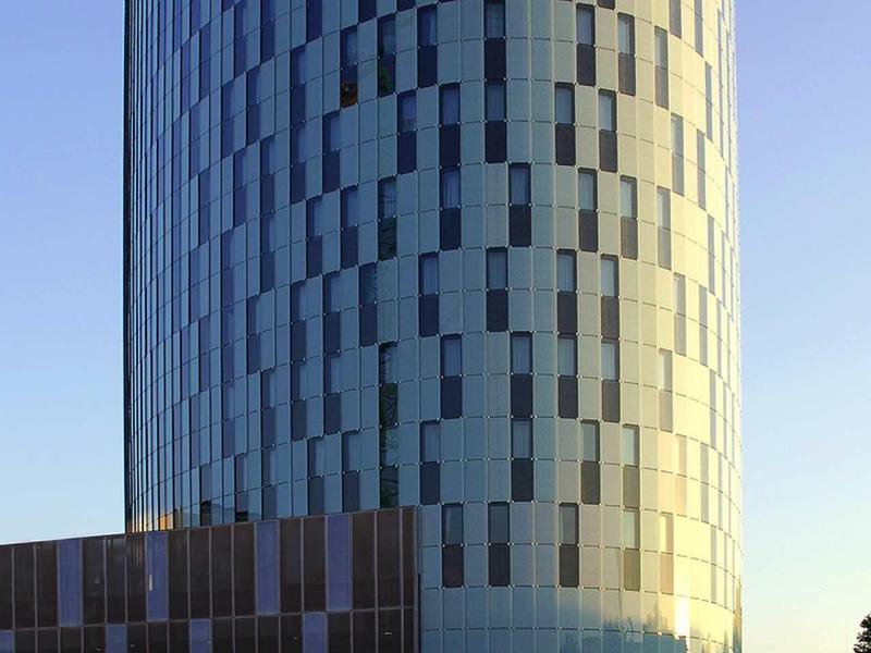 Nowoczesny, okrągły wieżowiec z fasadą okien pod czystym niebem.