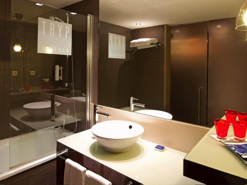 Nowoczesna łazienka hotelowa z umywalką, lustrem i wanną.