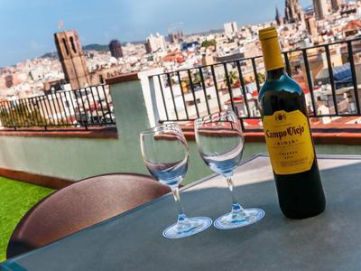 Bottiglia di vino e due bicchieri su un tavolo con vista su una città e un terrazzo sul tetto.