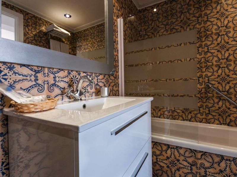 Nowoczesna łazienka z wzorzystymi płytkami, białą umywalką i wanną.