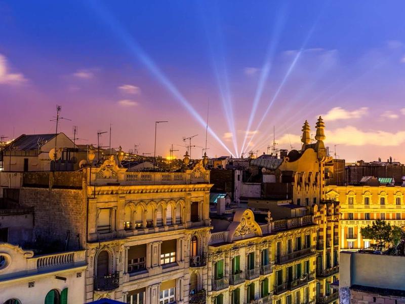 Städtische Dächer bei Sonnenuntergang mit hellen Lichtstrahlen am violetten Himmel.