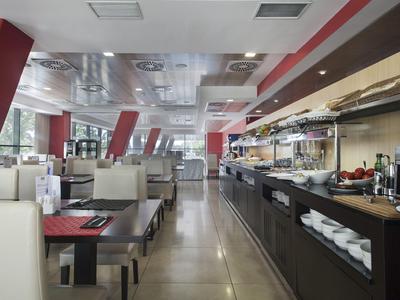 Modernes, helles Hotelrestaurant mit Buffet und weißen Sitzbänken entlang der Fenster.