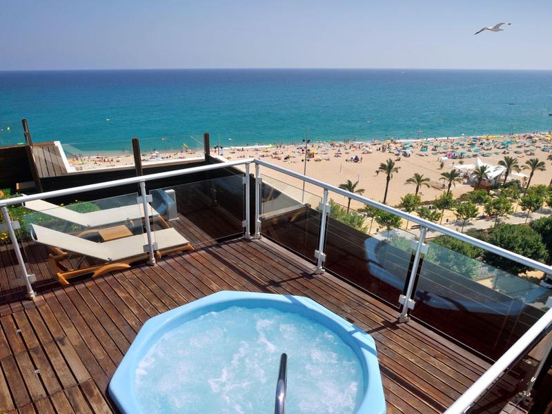 Bain à remous sur une terrasse sur le toit avec vue sur la mer et plage de sable en arrière-plan.