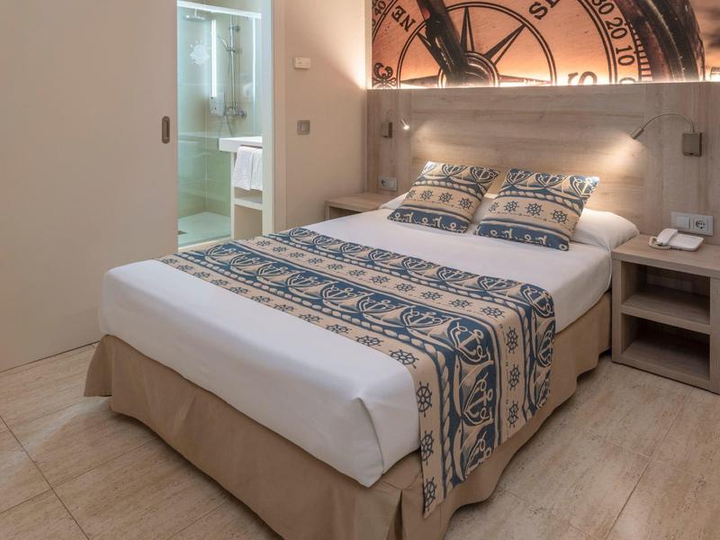 Chambre d'hôtel moderne avec lit double et literie à motif nautique.