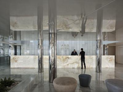 Reception di un hotel moderno con banconi in marmo lucido e due persone al banco.