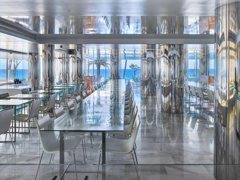 Large modern dining hall with shiny surfaces and big windows, filled with natural daylight.