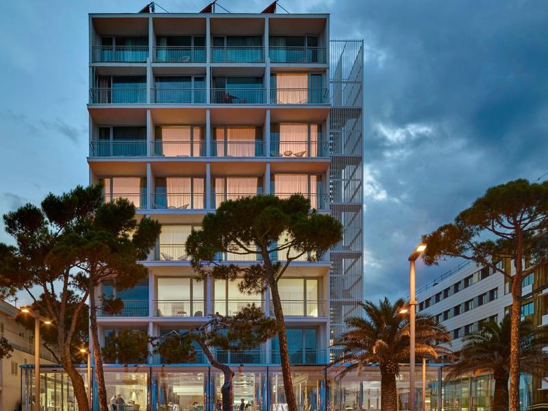 Modern hotel building with multiple floors and large glass windows at dusk.
