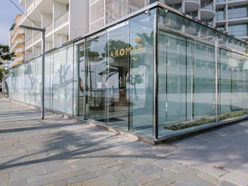 Modern hotel building with glass entrance and rounded balconies under sunny weather.