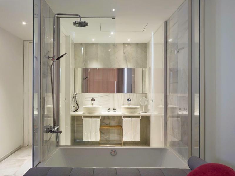 Modern bathroom with large shower, vanity, and glass wall to adjacent room.