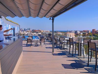 Terrasse ouverte avec tables, chaises et vue sur un village sous un ciel clair.