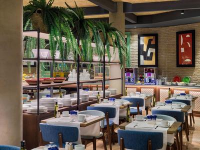 Salle à manger moderne avec des chaises bleues et des plantes suspendues décoratives au plafond.