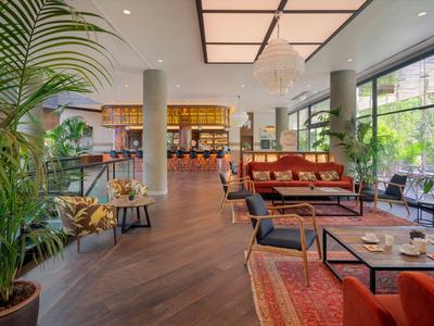 Espace lobby d'hôtel moderne avec des sièges confortables et beaucoup de lumière naturelle grâce aux grandes fenêtres.