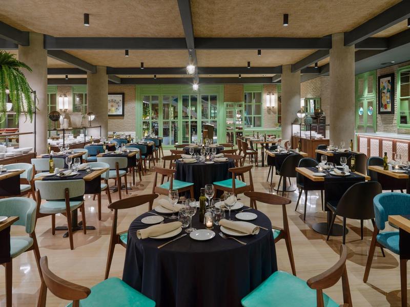 Elegante eetzaal met ronde tafels, houten stoelen en sfeerverlichting voor een gezellige ambiance.