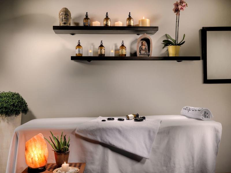 Ontspannende spa kamer met massagetafel, kaarsen, planten en rustgevende inrichting.