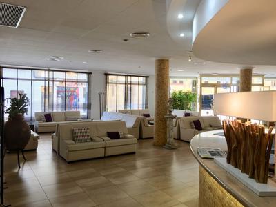 Lichte hotel lobby met banken, grote ramen en decoratieve elementen bij de receptie.