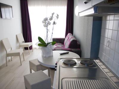 Kleine keuken met fornuis en eetgedeelte in een modern, licht appartement.