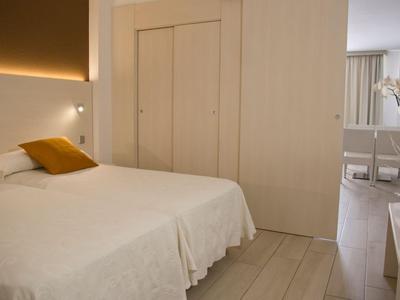 Lichte slaapkamer met tweepersoonsbed, witte muren en moderne verlichting.