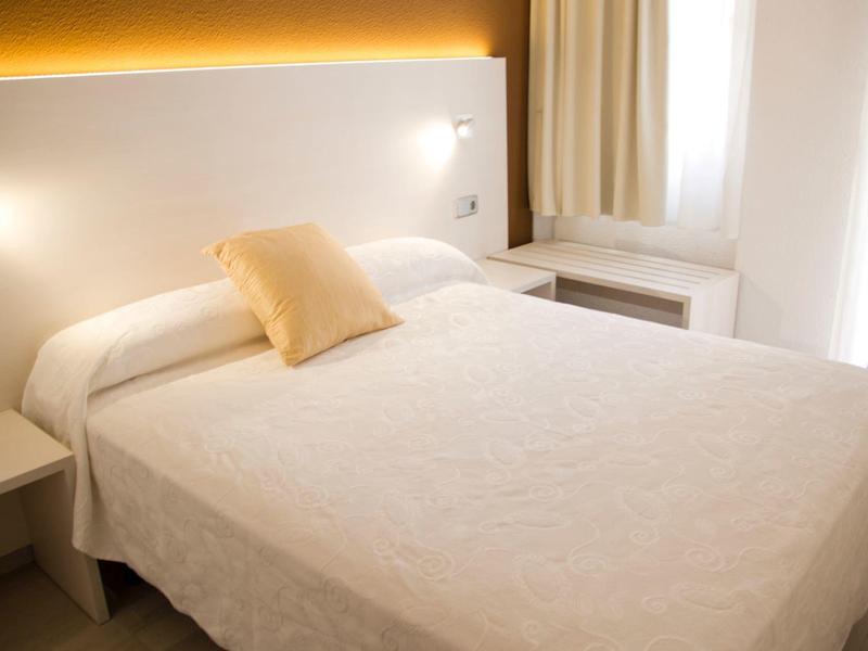 Przytulny pokój hotelowy z podwójnym łóżkiem, stolikami nocnymi i ciepłym oświetleniem.