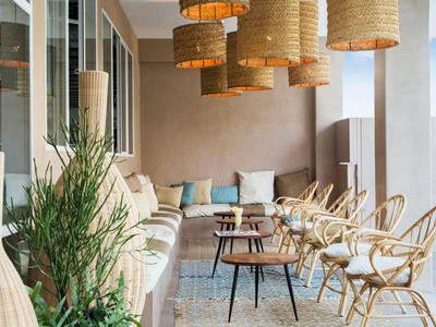 Terrasse confortable avec sièges, coussins et abat-jour naturels.