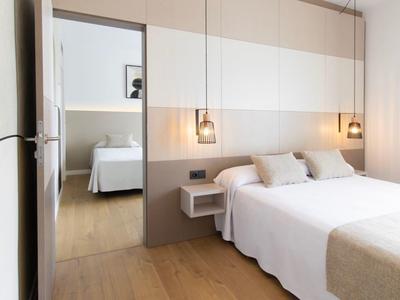 Helles Hotelzimmer mit Doppelbett, Nachttischen, modernen Lampen und Holzboden.