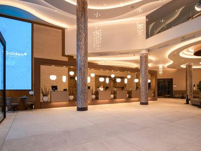 Moderne Hotellobby mit beleuchteten Rezeptionstresen und eleganten Säulen.