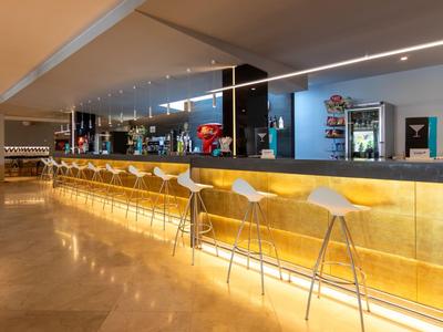 Moderner Hotelbarbereich mit stilvollen Barhockern und beleuchtetem Tresen.