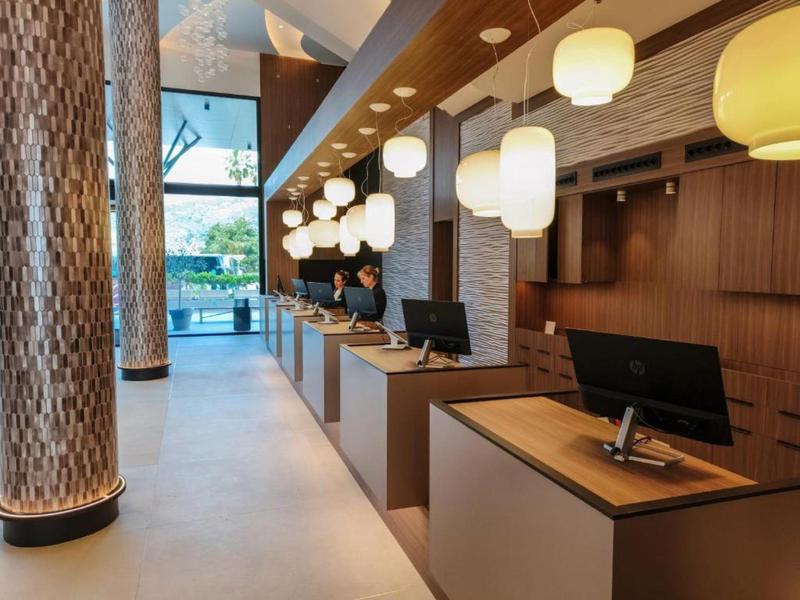 Moderner Hotellobby-Empfang mit Holztheken und beleuchteten Säulen.