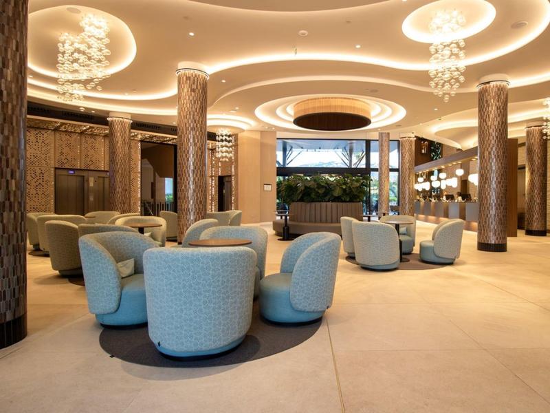 Großer Hotel-Loungebereich mit runden Sesseln, eleganten Säulen und warmem Licht.