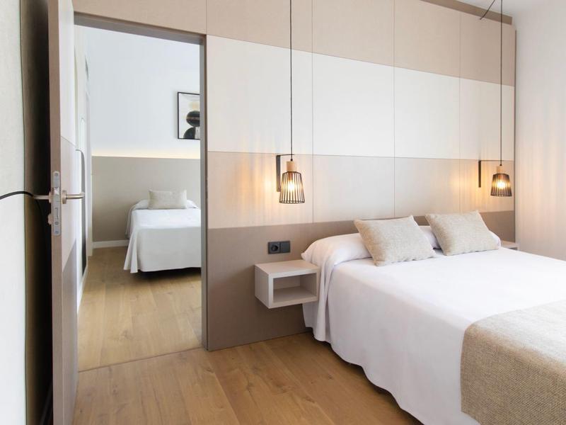 Helles Hotelzimmer mit Doppelbett, Nachttischen, modernen Lampen und Holzboden.