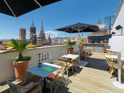 Terrazza sul tetto con tavoli, sedie, ombrelloni e vista sulla città e sul mare.