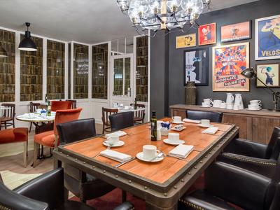 Sala riunioni elegante con grande tavolo in legno, poltrone in pelle e poster decorativi alle pareti.