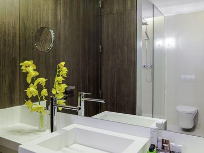 Moderne badkamer met witte wastafel, gele bloemen en houten muren.