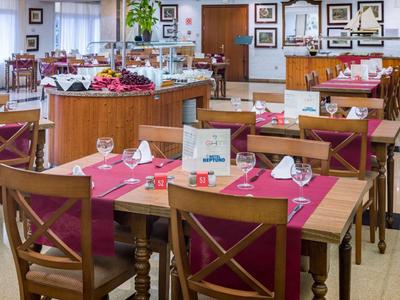 Helles Restaurant mit Holztischen, roten Tischsets und dekorativer Wandgestaltung.