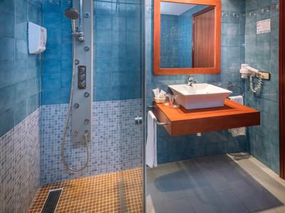 Modern badkamer met douche, wastafel, spiegel en haardroger.