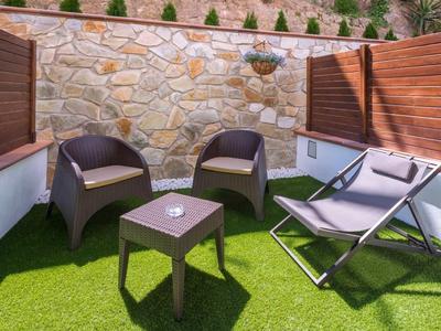 Gezellig zitgedeelte met stoelen en ligstoelen op kunstgras naast houten wanden.