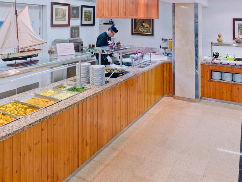 Buffetruimte met grote houten balie, salades en een model zeilboot als decoratie.