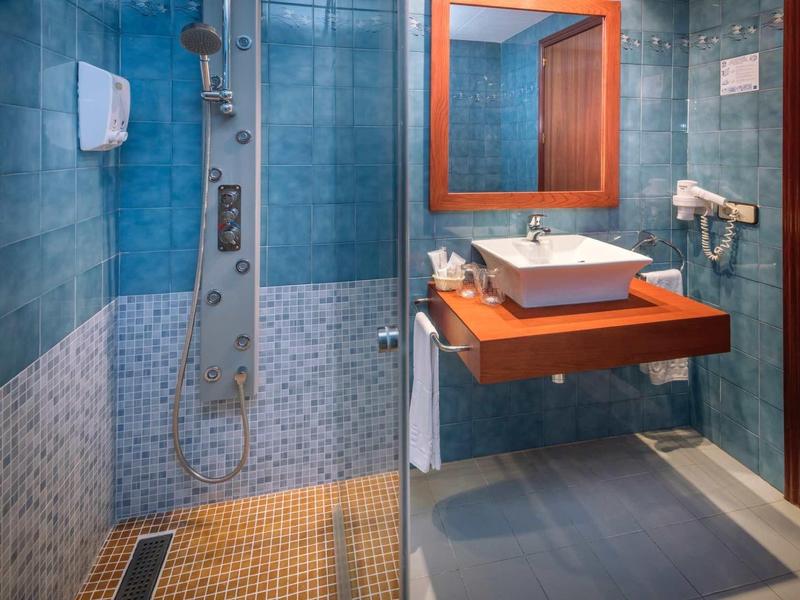 Modern badkamer met douche, wastafel, spiegel en haardroger.