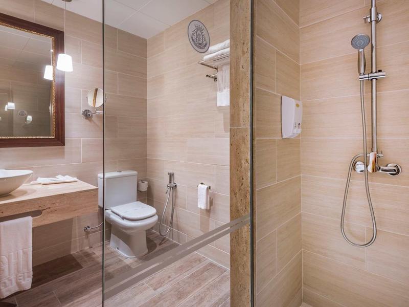 Moderne hotelbadkamer met douche, toilet, wastafel en licht houten design.