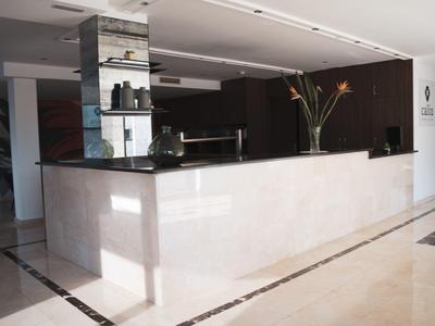 Moderner Empfangstresen aus hellem Stein mit schwarzer Arbeitsfläche und Blumendekoration.