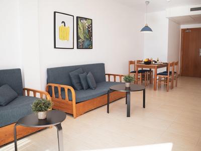 Světý obývací prostor se dvěma pohovkami, stoly, rostlinami a jídelním stolem v pozadí