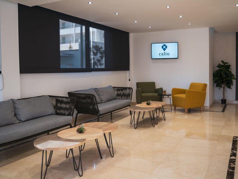 Moderní čekárna se šedými pohovkami, křesly a konferenčními stolky.