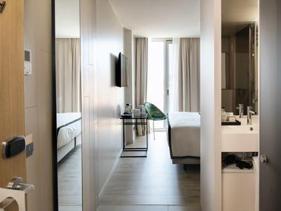 Moderner Hotelzimmerflur mit Blick auf Bett und Bad, hell und minimalistisch eingerichtet.