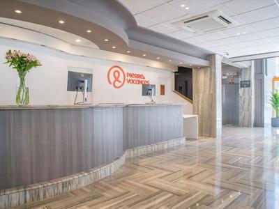 Moderne Hotelrezeption mit langer Theke, Blumenvasen und Parkettboden in hellem Ambiente.