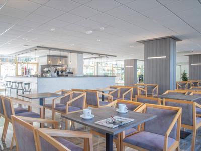 Modernes Hotelrestaurant mit Holzmöbeln und Cafébar im hellen Ambiente.