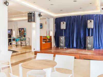 Moderne evenementenruimte met podium, geluidsinstallatie en zitplaatsen in een lichte omgeving.