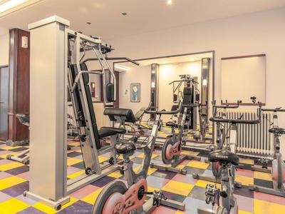 Lichte sportschool met krachtapparatuur en kleurrijke geruite vloer in een hotel.