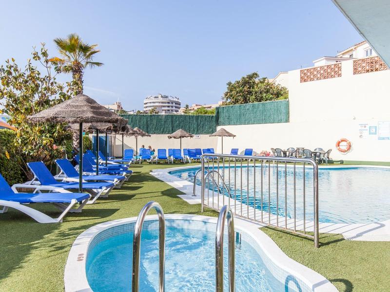 Zewnętrzny basen z leżakami i parasolami pod niebieskim niebem