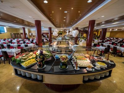 Großer Buffetbereich mit vielfältigen Speisen, rundem zentralem Buffet und festlich gedeckten Tischen.