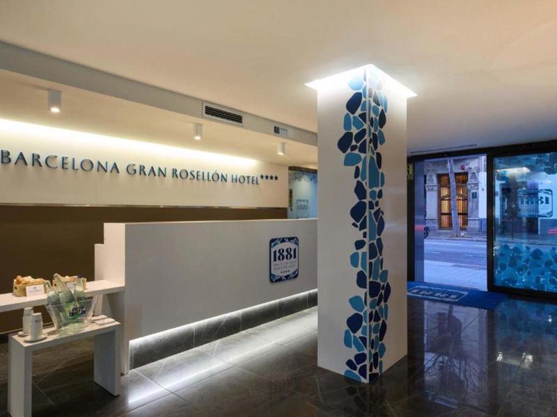 Moderner Hotel-Lobby-Eingangsbereich mit weißer Rezeption und dunklem Mosaik an Säule.