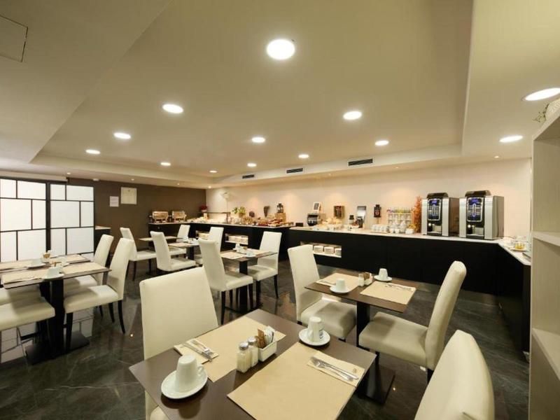 Moderner Café-Raum mit weißen Stühlen, Tischen, Theke und Beleuchtung an der Decke.